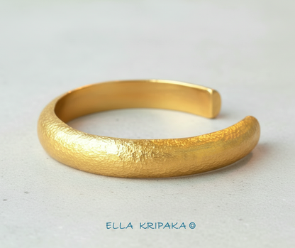 24k 9999 gold hammered cuff bracelet Ancient Rome style on a white craft paper surface, artist-jeweler 'Ella Kripaka' branding