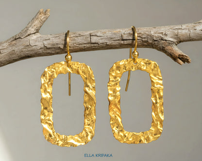 Organic hammered uneven 24k 9999 Gold hoops earrings hanging on a branch and on a grey background, and with 'ELLA KRIPAKA' branding