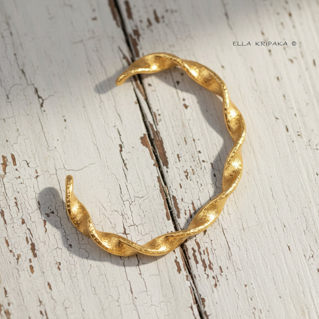 Twisted Viking hammered 24k 9999 gold bracelet cuff on a old white old wooden background, branding artist-jeweler name 'Ella Kripaka'