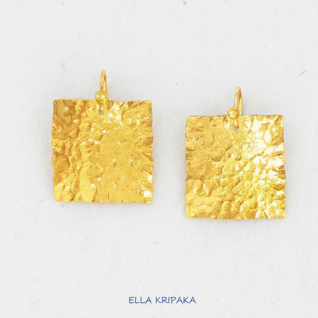 Organic 24k gold square earrings with textured reliefs on a white craft paper background with 'Ella Kripaka' branding