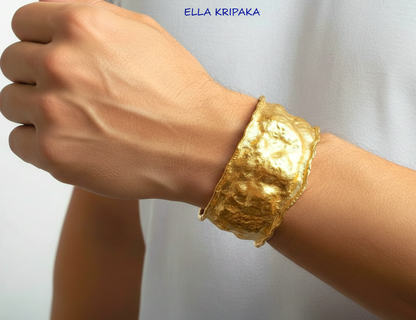 Organic 24k gold hammered bracelet cuff with a textured surface on a man's wrist and with blurred light background, branded 'Ella Kripaka'