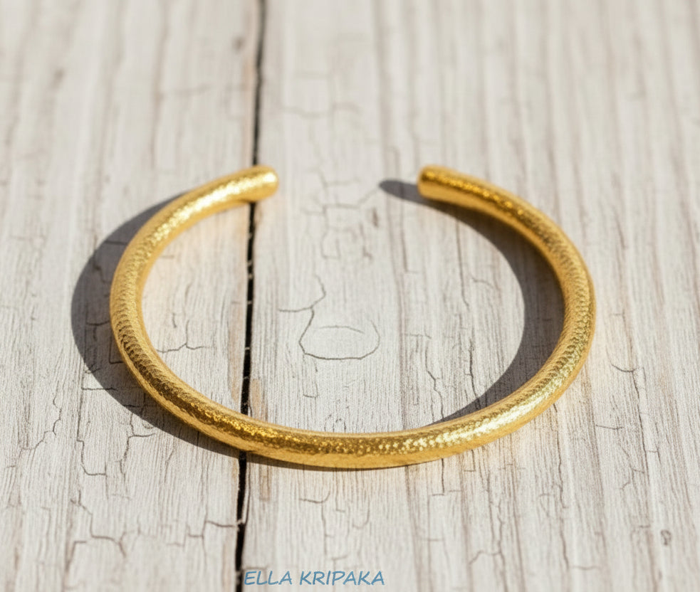 Hammered 24k 9999 gold rounded bracelet cuff Ancient Rome style on a old wooden background, branding artist-jeweler name 'Ella Kripaka'