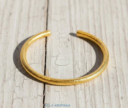 Hammered 24k 9999 gold rounded bracelet cuff Ancient Rome style on a old wooden background, branding artist-jeweler name 'Ella Kripaka'