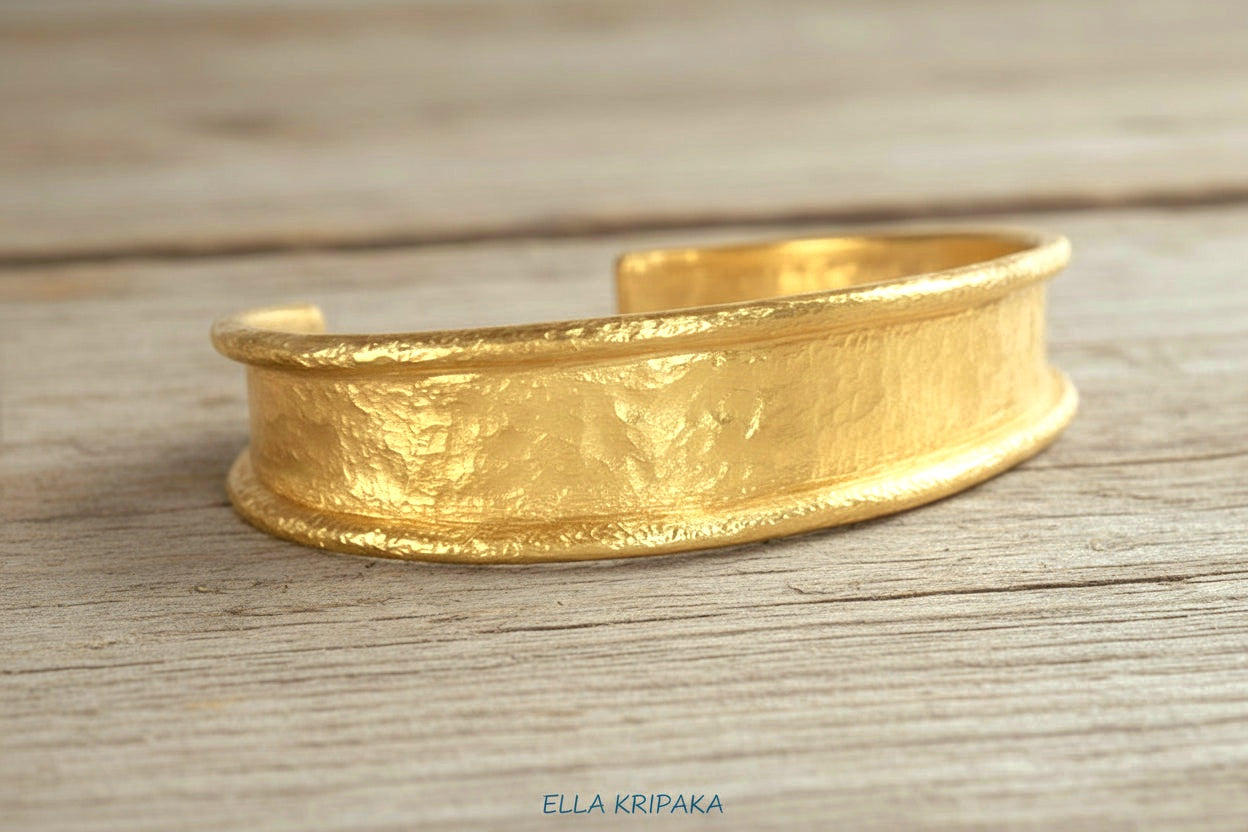 Hammered 24k 9999 gold bracelet cuff Ancient Rome style on a old wooden background, branding artist-jeweler name 'Ella Kripaka'