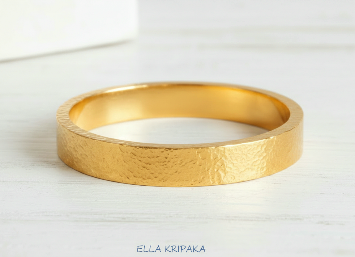 Hammered 24k Gold thick bangle textured bracelet on white wooden table surface, artist's name 'Ella Kripaka' branding