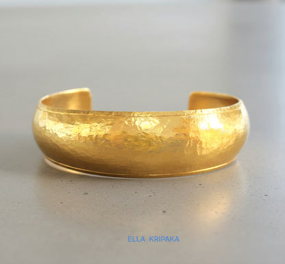 24k 9999 gold hammered Ancient Rome convex  cuff bracelet on a grey concrete surface, branded 'Ella Kripaka'