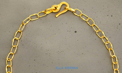 22k gold hammered chain necklace with thick hook clasp on grey concrete background, artist-jeweler's name 'Ella Kripaka' branding
