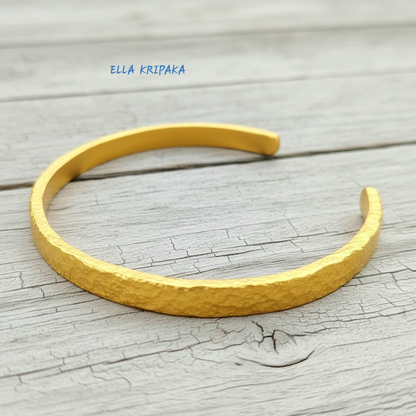 Hammered 24k 9999 gold cuff thick bracelet Ancient Rome style on old white wooden background, artist-jeweler's name 'Ella Kripaka'