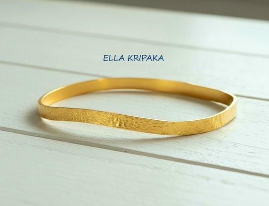 Uneven hammered 24k 9999 Gold organic bangle bracelet on white wooden surface, artist's name 'Ella Kripaka' branding