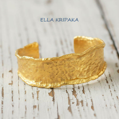 Organic hammered 24k 9999 gold bracelet uneven cuff on a old white wooden background, branding artist-jeweler name 'Ella Kripaka'