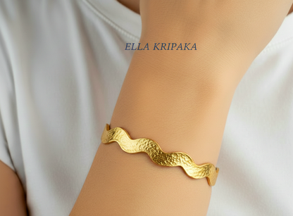 Hammered 24k 9999 Gold wavy bangle bracelet Ancient Egypt style worn on person's hand, artist's name 'Ella Kripaka' branding