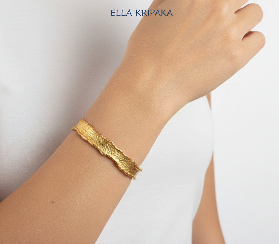 Organic Hammered 24k Gold Bangle Bracelet Textured with uneven thick edges worn on a woman's hand and white background, branding artist-jeweler 'Ella Kripaka'