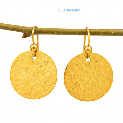 Hammered 24k gold, pure 9999 gold disk earrings with shiny forged gold textures hanging on a branch and with white  background, artist-jeweler 'Ella Kripaka' branding