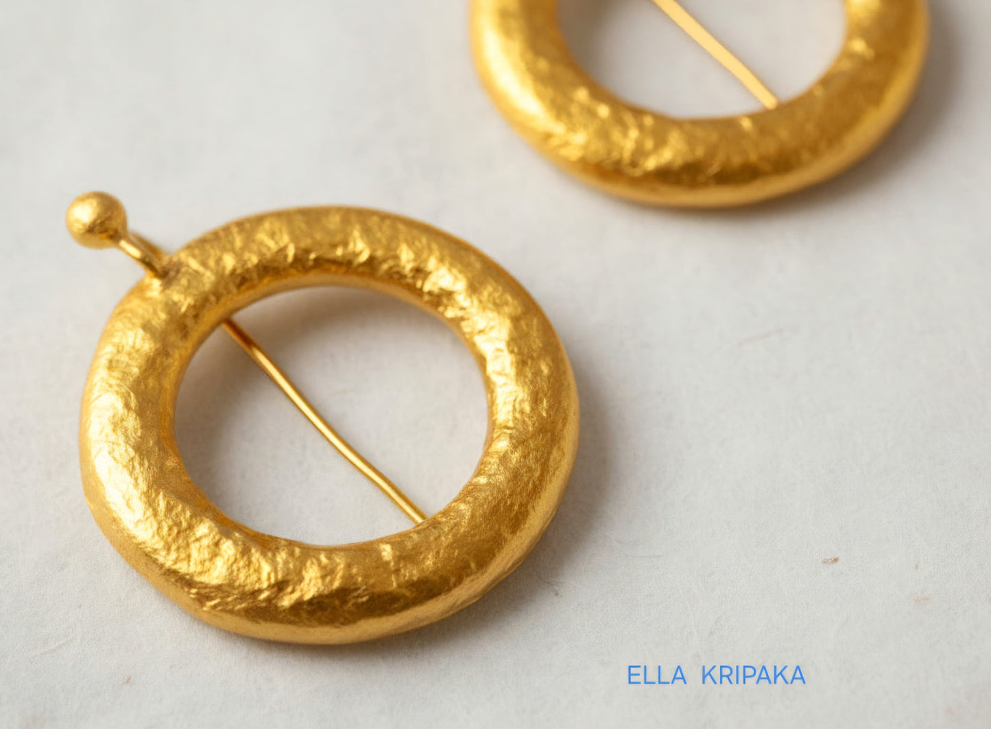 Hammered 24k 9999 Gold convex hoops earrings Ancient Rome and Byzantine style on a white paper background, and artist-jeweler's name 'Ella Kripaka' branding