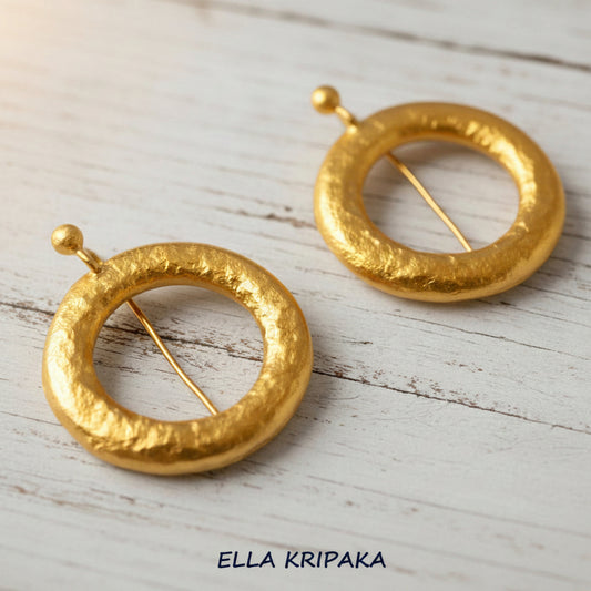 Hammered 24k 9999 Gold convex hoops earrings Ancient Rome and Byzantine style on a white rustic wooden background, and artist-jeweler's name 'Ella Kripaka' branding