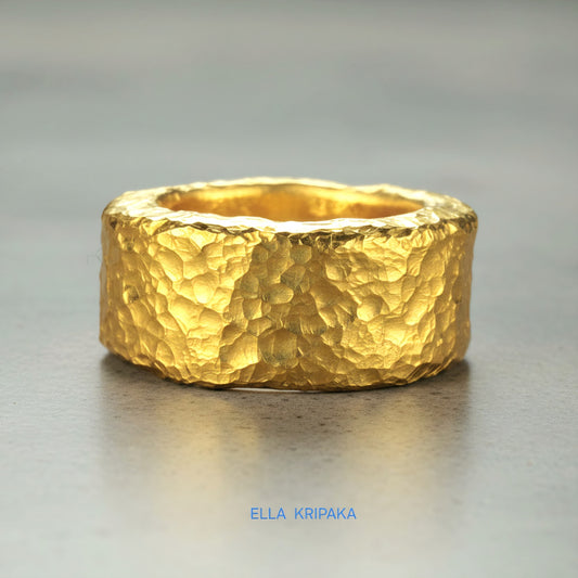 Hammered 24k 9999 Gold thick ring Ancient Rome style with textured gold on a grey concrete background, branded 'Ella Kripaka'