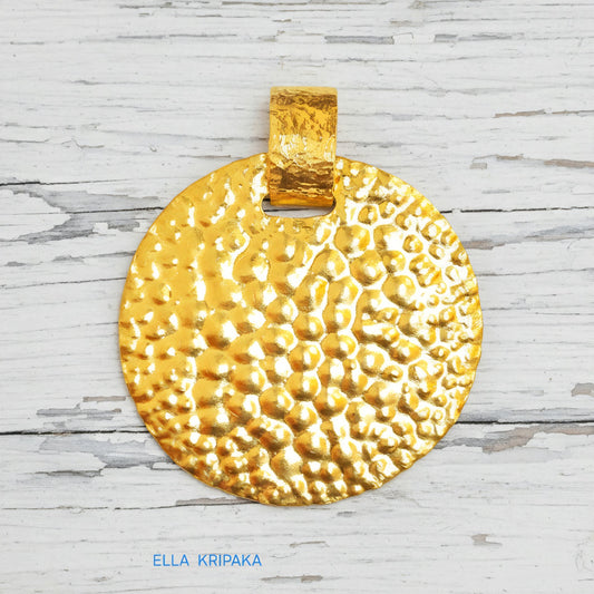 Organic hammered 24k gold, pure 9999 gold disk pendant with shiny forged gold textures on  white old wooden surface, artist-jeweler 'Ella Kripaka' branding