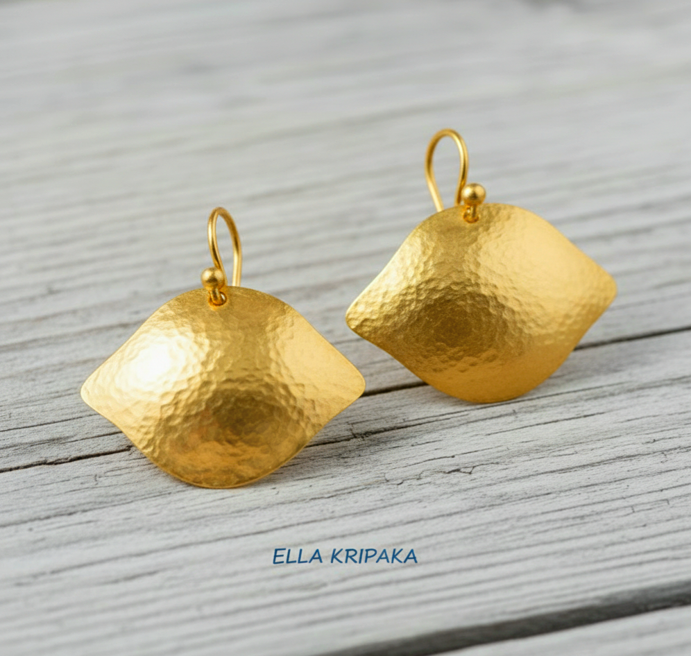 24k 9999 gold hammered Byzantine convex earrings with shiny gold textures are on light old wooden background, artist-jeweler's name 'Ella Kripaka'