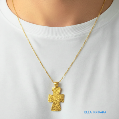 Hammered 24k gold textured cross pendant with chain worn by a person with white t-shirt, artist-jeweler 'Ella Kripaka' branding