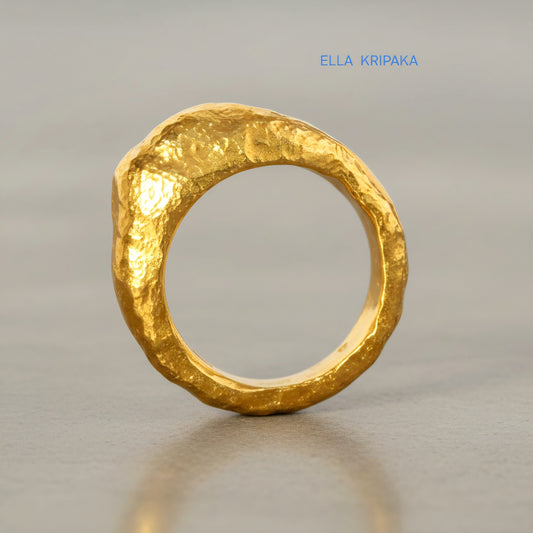Hammered organic 24k Gold 9999 gold uneven signet thick ring with textured gold on a grey concrete background, branded 'Ella Kripaka'