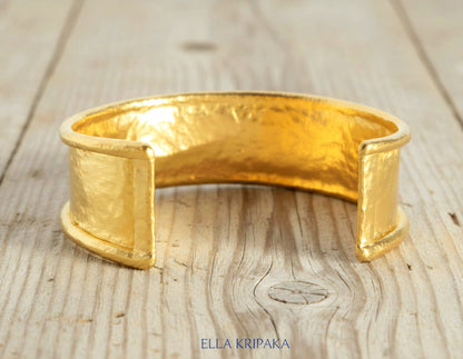 Hammered 24k 9999 gold bracelet cuff Ancient Rome style on a old wooden background, branding artist-jeweler name 'Ella Kripaka'