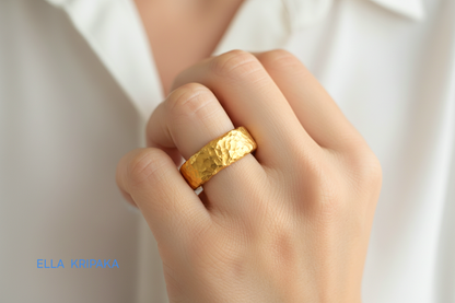 Hammered 24k 9999 Gold thick uneven ring organic with a textured gold surface worn on woman's finger and on a blurred background, branded 'Ella Kripaka'