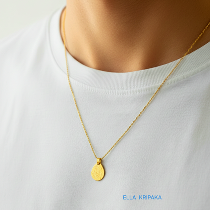 Hammered 24k gold, pure 9999 gold drop pendant on chain worn by a man and with white t-shirt and on grey background, artist-jeweler 'Ella Kripaka' branding