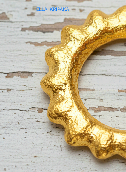 24k 9999 gold hammered convex Sun pendant on a white old wooden surface, branded 'Ella Kripaka'