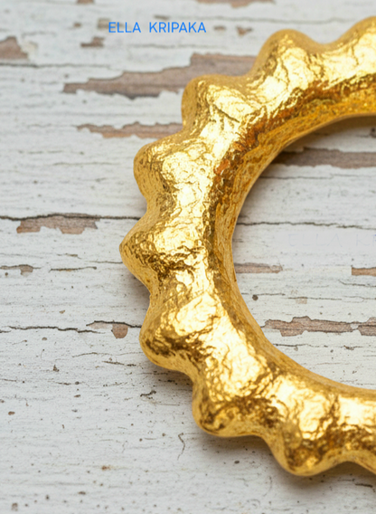 24k 9999 gold hammered convex Sun pendant on a white old wooden surface, branded 'Ella Kripaka'