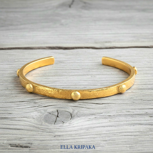 24k gold hammered cuff textured bracelet with convex rounds on light rustic wooden surface, artist 'Ella Kripaka' branding