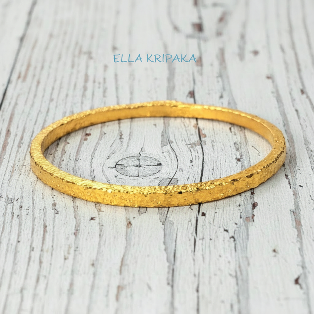 Hammered 24k 9999 gold bangle thick bracelet Ancient Rome style on a white wooden background, artist-jeweler name 'Ella Kripaka'
