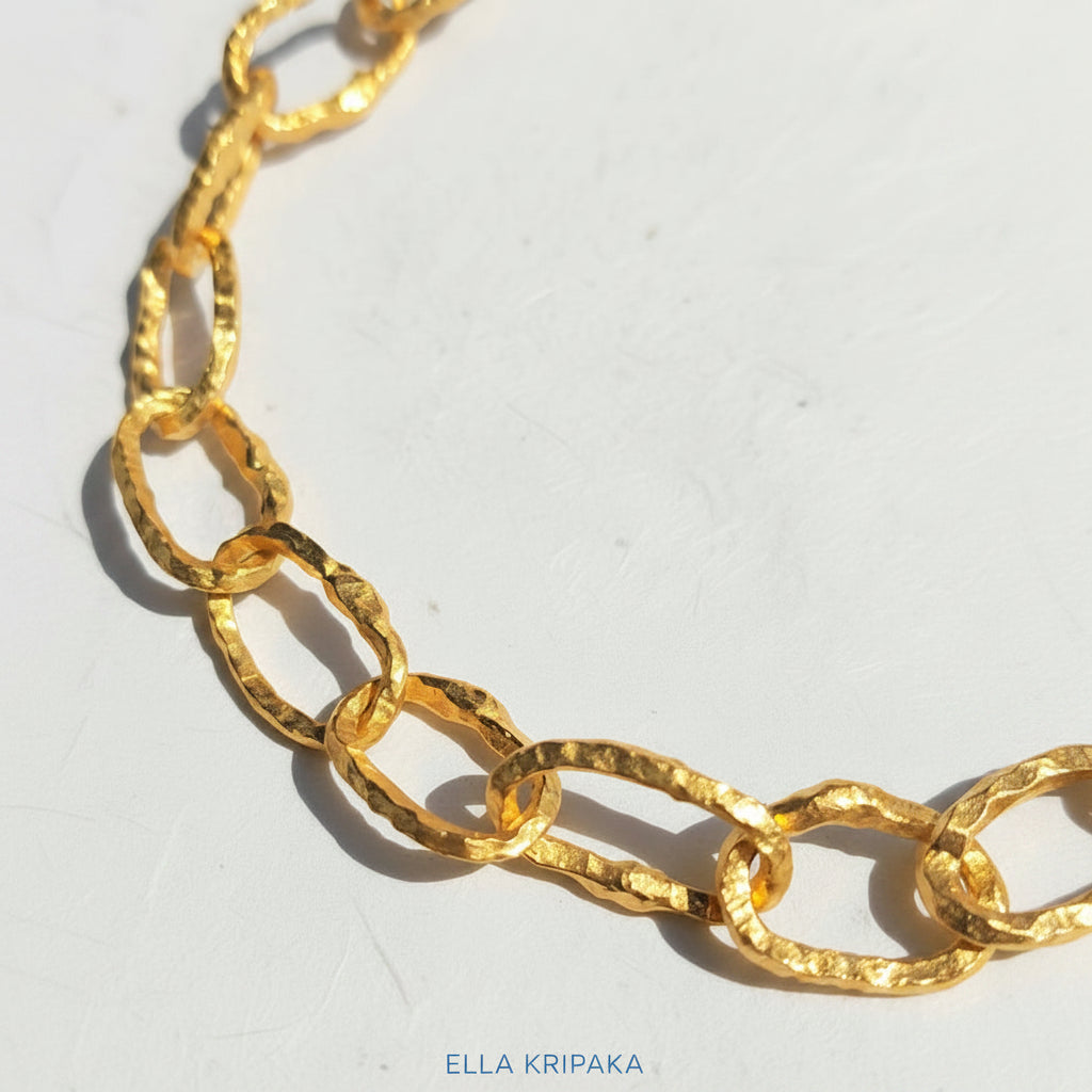 Organic 24k Gold hammered uneven textured chain necklace on a white craft paper surface, with artist 'Ella Kripaka' branding