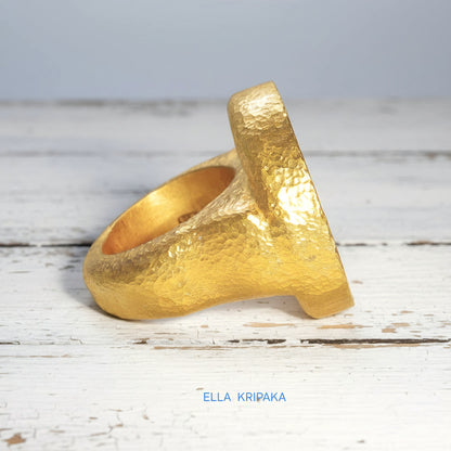 Hammered 24k 9999 Gold thick ring disk signet Ancient Rome style and Byzantine style with a textured gold on a white old wooden background, branded 'Ella Kripaka'