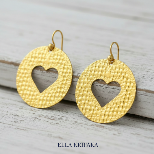 24k gold hammered textured disks with hearts earrings and with shiny big textures and on old white wooden background, artist-jeweler's name 'Ella Kripaka'