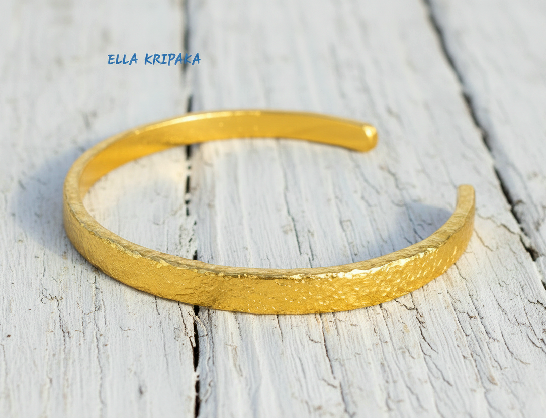 Hammered 24k 9999 gold cuff thick bracelet Ancient Rome style on old white wooden background, artist-jeweler's name 'Ella Kripaka'