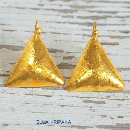 Hammered 24k gold, pure 9999 gold convex triangle earrings with shiny forged gold textures on white old wooden surface, artist-jeweler 'Ella Kripaka' branding