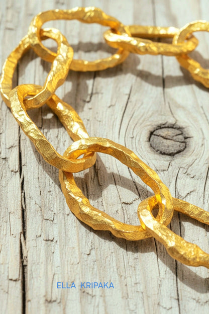 Hammered 24k 9999 gold organic bracelet chain with hammered uneven textures and a thick hook clasp on white old wooden surface, artist name 'Ella Kripaka'