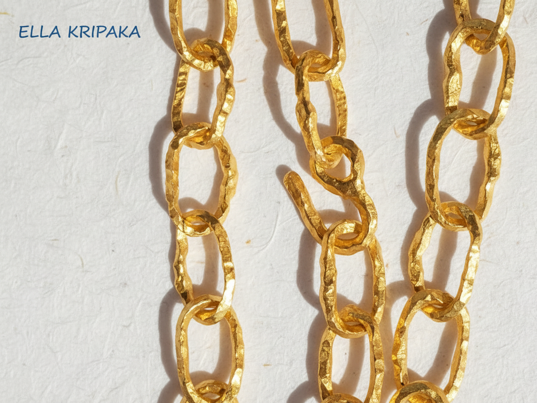 Organic 24k Gold hammered uneven textured chain 12mm of width and with thick hook clasp on a white craft paper surface, with artist 'Ella Kripaka' branding