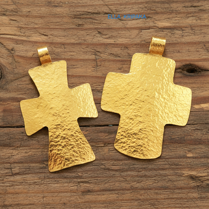 Two hammered 24k gold textured cross pendant on rustic old wooden surface, creator artist-jeweler 'Ella Kripaka' branding