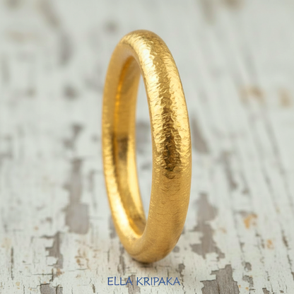 Hammered 24k gold rounded textured ring on a white old rustic wooden surface with 'Ella Kripaka' branding