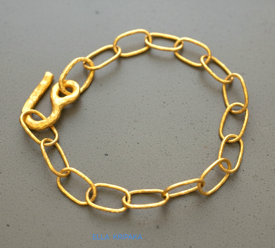 22k gold hammered chain bracelet with thick hook clasp on grey concrete background, artist-jeweler's name 'Ella Kripaka' branding