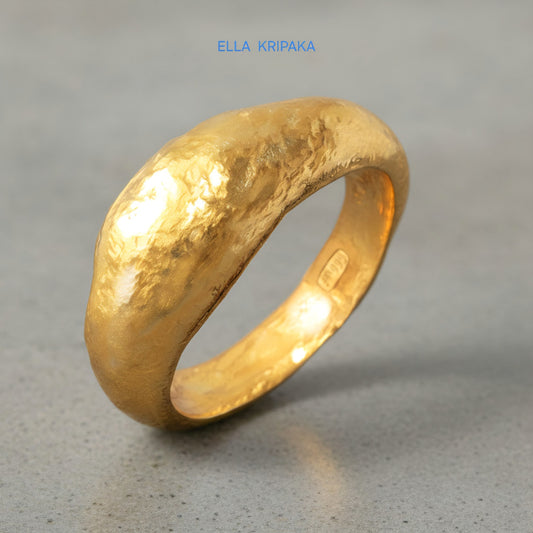 Hammered organic 24k Gold 9999 gold uneven signet thick ring with textured gold on a grey concrete background, branded 'Ella Kripaka'