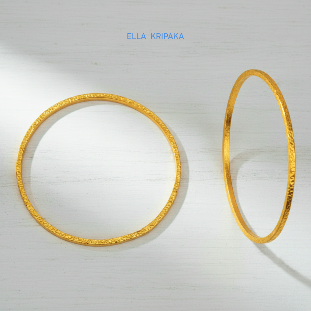 22k gold hammered two thick bangles bracelets Ancient Rome style on a white wooden surface, artist-jeweler 'Ella Kripaka' branding