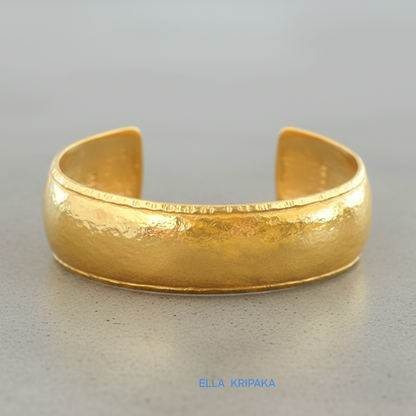 24k 9999 gold hammered Ancient Rome convex  cuff bracelet on a grey concrete surface, branded 'Ella Kripaka'