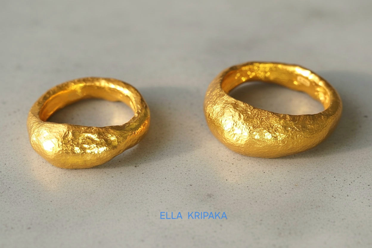 Hammered organic 24k Gold 9999 gold uneven two signets thick rings with textured gold on a grey concrete background, branded 'Ella Kripaka'