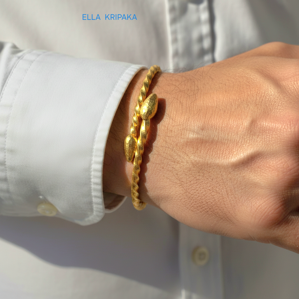 Twisted 24k gold hammered bracelet with thick ends and with textured design is worn by a man on wrist and on white shirt background, branded artist 'Ella Kripaka'