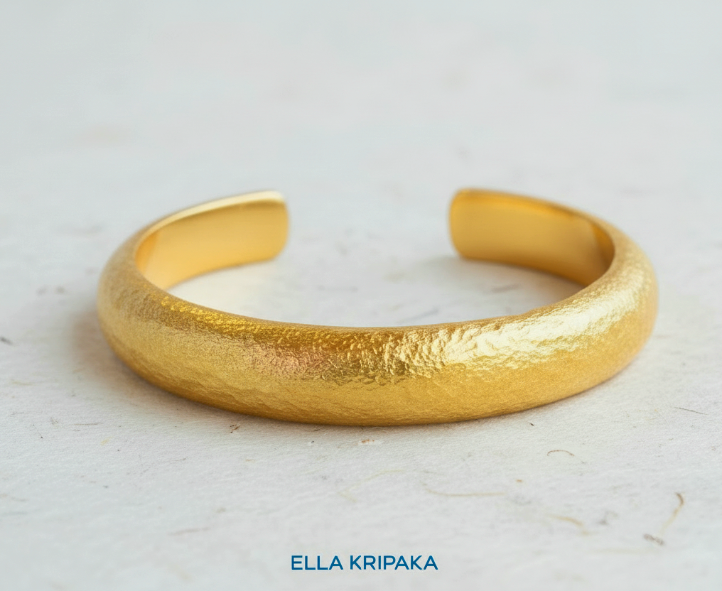 24k 9999 gold hammered cuff bracelet Ancient Rome style on a white craft paper  surface, artist-jeweler 'Ella Kripaka' branding