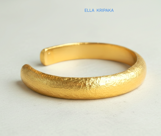 24k 9999 gold hammered cuff bracelet Ancient Rome style on a white craft paper  surface, artist-jeweler 'Ella Kripaka' branding