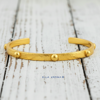 24k gold hammered cuff textured bracelet with convex rounds on white rustic wooden surface, artist 'Ella Kripaka' branding