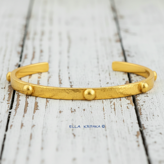 24k gold hammered cuff textured bracelet with convex rounds on white rustic wooden surface, artist 'Ella Kripaka' branding